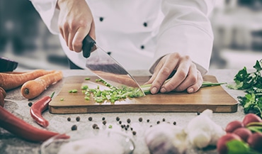 A chef cutting celery on a cutting board